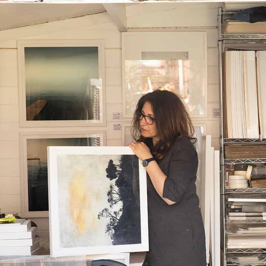 British Artist, Nadia Attura, holding an artwork in her studio